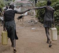Women holding hands and carrying water in Uganda, Africa