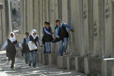 School girls running next to the security barrier in east Jerusalem