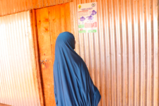 Woman in Somaliland reading a Covid-19 awareness sticker. Photo: SOYDAVO
