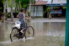 Burmese girl riding bicycle in flood area