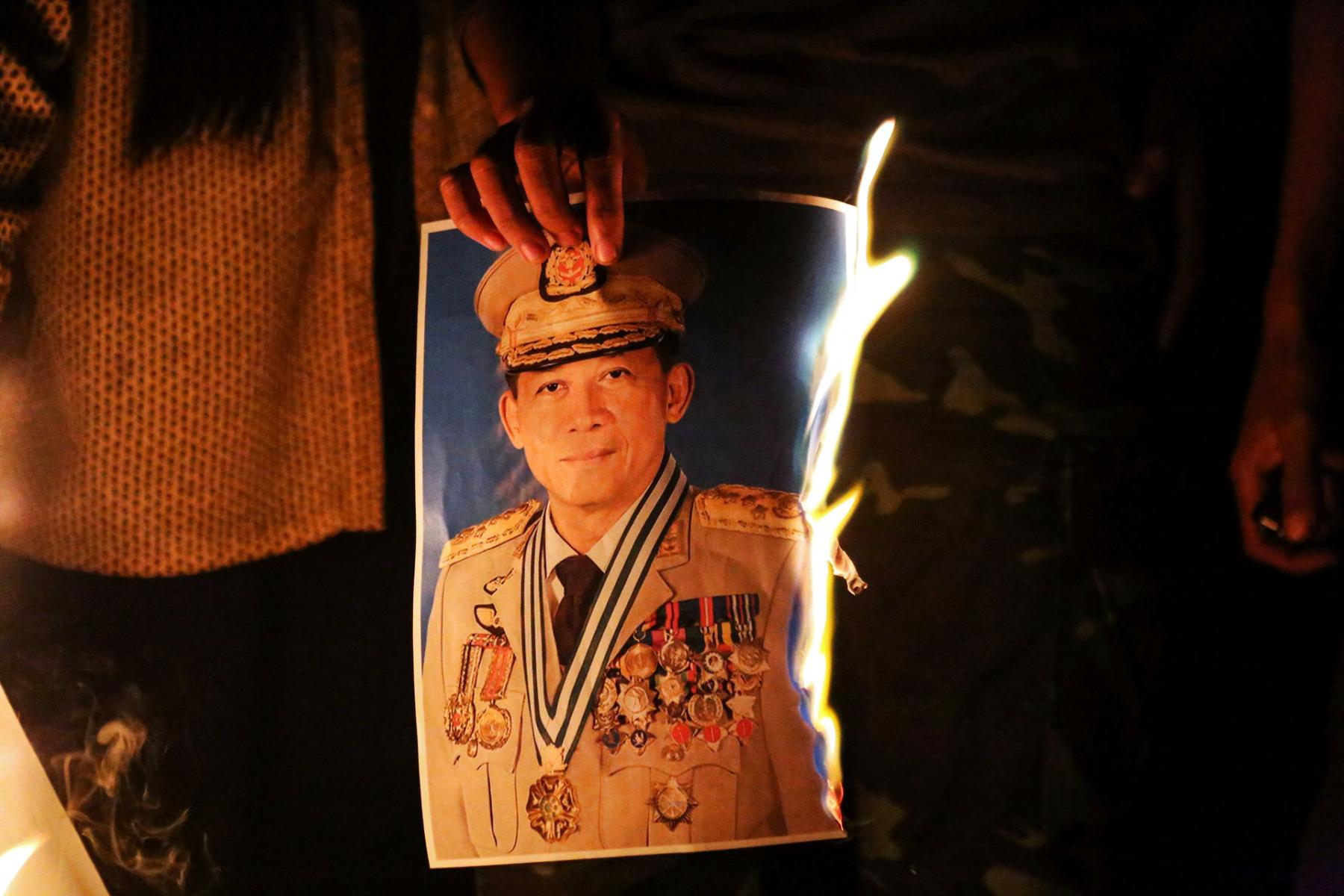 People burn a portrait of Army chief General Min Aung Hlaing as they protest against the military coup, in Mandalay