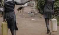 Women holding hands and carrying water in Uganda, Africa